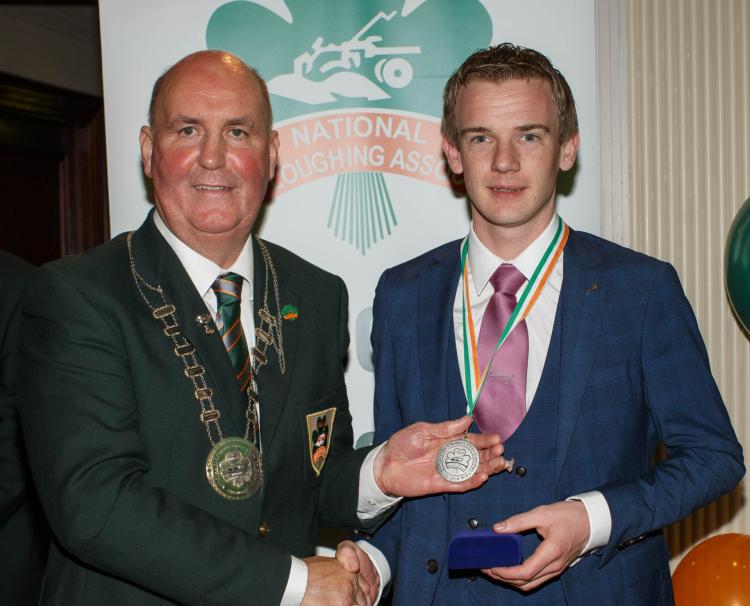 Gerard Mahon is presented with his silver medal by NPA President James Sutton for the Macra 2 Furrow Conventional Plough Class
