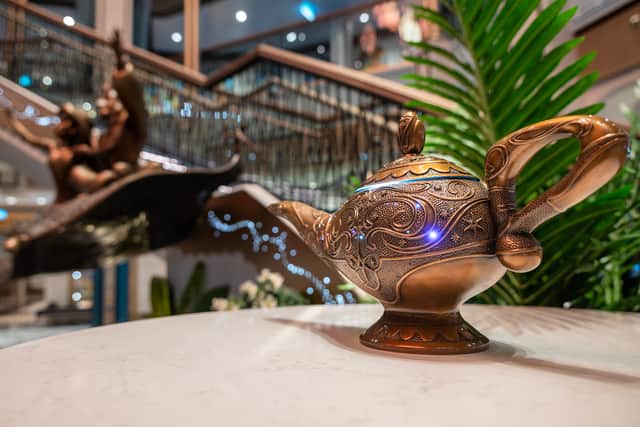 A main atrium evoking the fictional Arabian kingdom of Agrabah from Aladdin ascends three decks, lit by an ornate, gilded chandelier, which changes colour throughout the day.