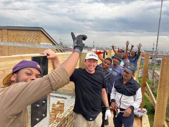 Peter Lyons with local workers after placing a roof beam on the new multipurpose hall in the township of Delft.