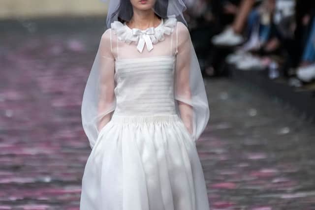 This season’s bride donned a strappy white dress with a pleated calf-length skirt, long-sleeved tulle overlay and ruffled collar.