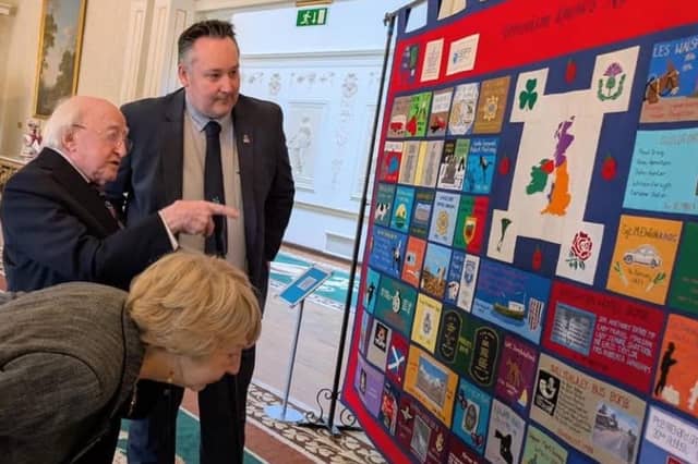 Michael D and Sabina Higgins discuss one of the quilts with Kenny Donaldson.