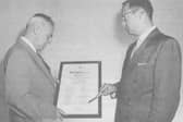 George Browne, on the left, receiving a certificate of recognition for his life-saving radio work from a member of the US Embassy.