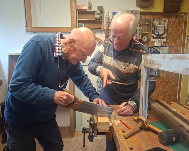 George Cunningham tries out his newfound carpentry skills under the watchful eye of tutor Tom Roche