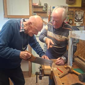 George Cunningham tries out his newfound carpentry skills under the watchful eye of tutor Tom Roche