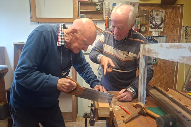 George Cunningham tries out his newfound carpentry skills under the watchful eye of tutor Tom Roche
