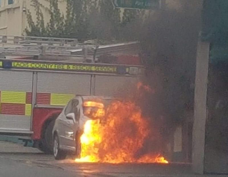 Fire service attending car in flames on main street in Laois town