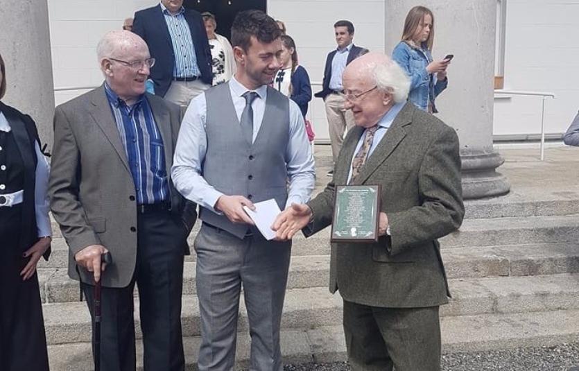 Gary Farrell, along with his parents Mary and Peader, presents President Michael D. Higgins with a plaque