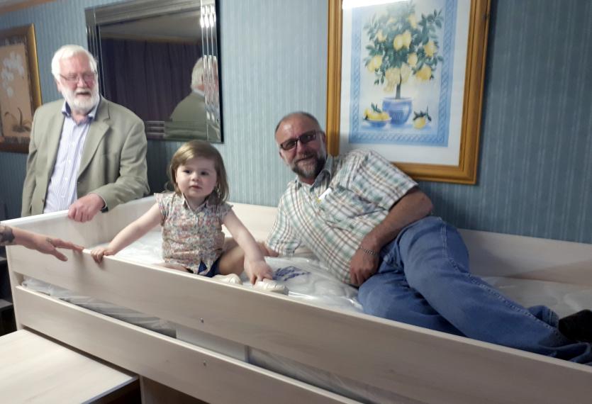 Oisin O'Sullivan (L) and employee Jimmy present little Sophia with her new bed